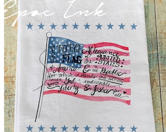 May include: White kitchen towel with a watercolor American flag design. The flag features red and white stripes and a blue field with stars. The text reads "I pledge allegiance to the flag..." and "Epoc Ink".
