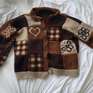 Op de afbeelding: Bruin en beige gehaakt vest met een patchwork design. Het vest heeft verschillende patronen, waaronder harten, bloemen en geruite vierkanten. De mouwen en manchetten zijn effen beige van kleur. Het vest is dichtgeknoopt.
