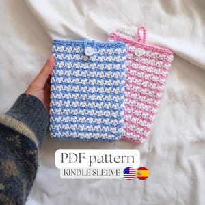 Puede incluir: Dos fundas Kindle de ganchillo hechas a mano, una azul y blanca, la otra rosa y blanca. Cada funda tiene un cierre de botón y un lazo. Se muestra el texto "PDF pattern" y "Kindle Sleeve".