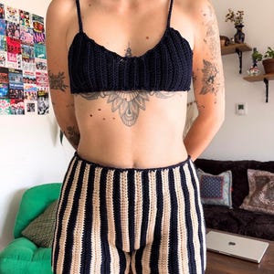May include: A navy blue crochet top with spaghetti straps and matching striped shorts. The shorts feature alternating beige and navy blue vertical stripes. The handmade set is a comfortable and stylish summer outfit.