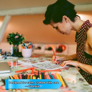 May include: A person is coloring in a detailed adult coloring book with colored pencils. The table has a floral pattern. The text on the image says "Designed for calm. Crafted with care - Georgia."
