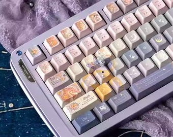 Könnte beinhalten: Eine individuelle mechanische Tastatur mit einem hellvioletten Rahmen und Tastenkappen in verschiedenen Pastellfarben. Die Tastenkappen weisen einzigartige Designs und Symbole auf, mit einigen gelben und blauen Tasten. Die Tastatur liegt auf einer dunkelblauen Oberfläche.