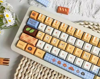 May include: A custom mechanical keyboard with a cream-colored frame and colorful keycaps. The keycaps feature various designs, including food-themed illustrations and patterned accents. The keyboard also has blue accent bars with cartoon graphics.