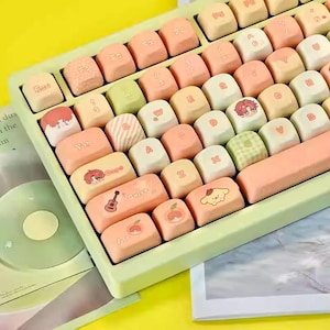 May include: A pastel-colored keyboard with custom keycaps. The keycaps feature various designs, including cartoon characters, fruits, and patterns. The keyboard's base is a light green, and the keycaps are in shades of peach, cream, and green.