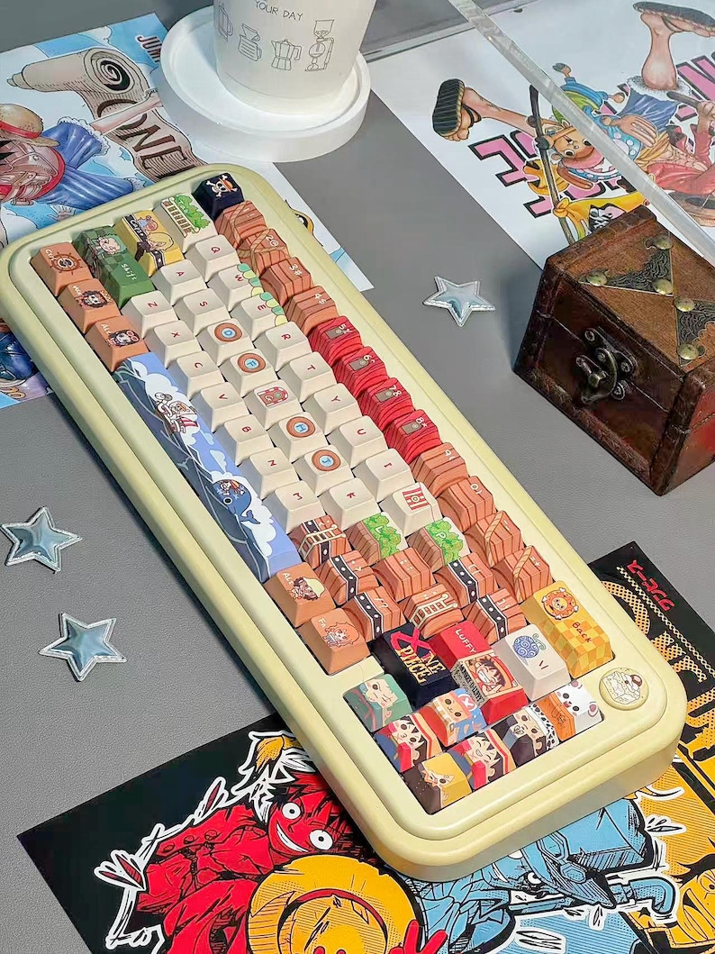 May include: A custom keyboard with a cream-colored frame and a variety of colorful keycaps. The keycaps feature illustrations of anime characters and other designs. The keyboard is surrounded by related artwork and a small wooden chest.