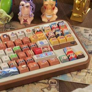 May include: A custom keyboard with character-themed keycaps and decorative figurines. The keycaps feature colorful illustrations of anime characters. The keyboard has a brown frame and is set on a surface with a map design.