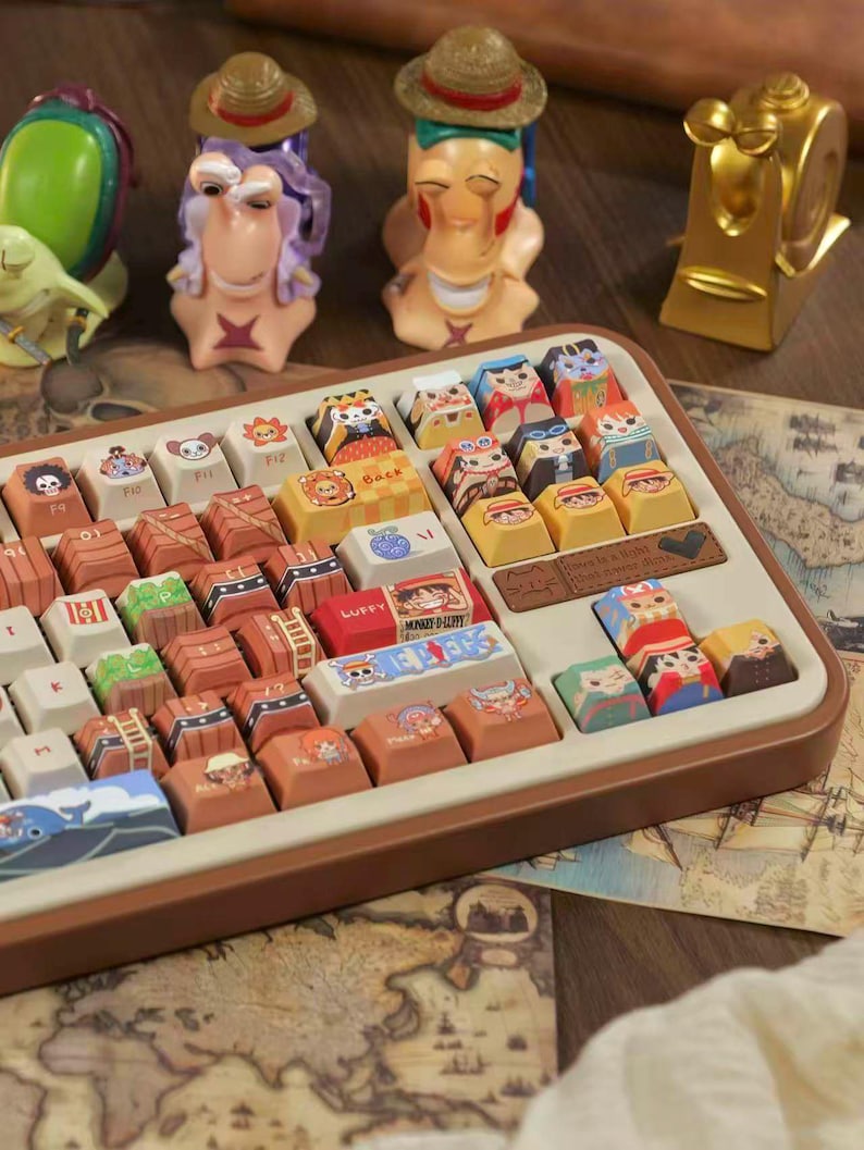 May include: A custom keyboard with character-themed keycaps and decorative figurines. The keycaps feature colorful illustrations of anime characters. The keyboard has a brown frame and is set on a surface with a map design.