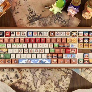 May include: A custom mechanical keyboard with a brown frame and white keycaps. The keycaps feature colorful cartoon character designs and themed artwork. The keyboard sits on a wooden surface with a map.