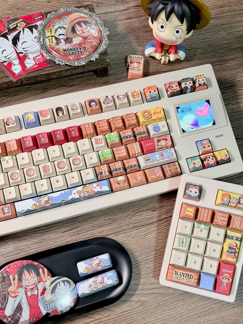 May include: A custom white keyboard with character-themed keycaps, including a small screen. The keycaps feature various cartoon characters and designs. Additional accessories include a matching number pad, coasters, and a figurine.