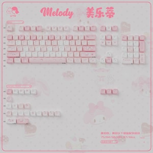 May include: A set of pink and white keyboard keycaps with the word "Melody" in pink script. The keycaps are arranged to show different keyboard layouts. The background is light pink with cartoon character illustrations.