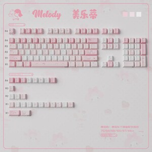 May include: A pink and white keyboard keycap set with the word "Melody" in pink script. The set includes various keycap sizes and configurations, with some keycaps featuring illustrations. The background is light pink.