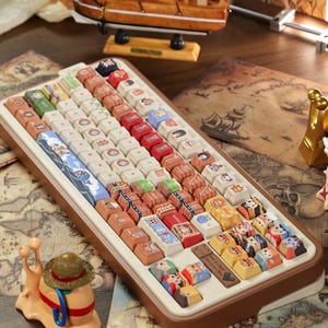May include: A custom keyboard with keycaps featuring various cartoon characters and nautical themes. The keyboard has a brown frame and a white base. A miniature sailboat and a snail figurine are also visible.
