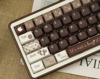 Puede incluir: Un teclado mecánico de estilo retro con una combinación de colores marrón y beige. Las teclas presentan una mezcla de marrón, beige y blanco con varios símbolos y texto. El teclado tiene forma rectangular y un marco marrón. La barra espaciadora tiene el texto "It's not a bug, it's a feature".