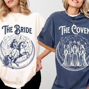 May include: Two oversized t-shirts, one cream and one navy blue. The cream shirt features the text "The Bride" above a graphic of a woman riding a unicorn inside a crescent moon. The navy blue shirt says "The Coven" with a graphic of three figures.