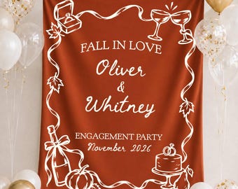 May include: A rust-colored fabric backdrop for an engagement party featuring white line art of a ring box, champagne flutes, a bottle, a pumpkin, and a cake. The text reads: FALL IN LOVE, Oliver & Whitney, ENGAGEMENT PARTY, November 2026.