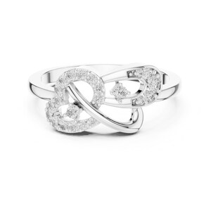 Può includere: Un anello d'argento con un design a forma di nota musicale, impreziosito da numerosi piccoli diamanti scintillanti. L'anello presenta un motivo fluido e intrecciato, con i diamanti che aggiungono brillantezza. La fascia è liscia e lucida, creando un contrasto con il design strutturato.