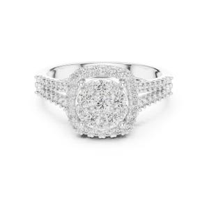 May include: A silver ring with a cluster of small, round, clear stones at the center, surrounded by a halo of smaller stones. The band features additional stones on either side of the central design. The ring is set against a white background.