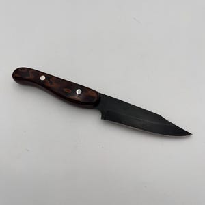 May include: A black blade knife with a dark brown wooden handle. The handle is secured with three silver rivets. The knife is designed for cutting and slicing.