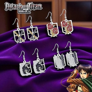 May include: A collection of silver-toned dangle earrings featuring designs from the anime series "Attack on Titan." The earrings showcase various symbols, including crossed swords, roses, a horse, and wings. The "Attack on Titan" logo is visible at the top.