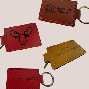 May include: Four leather keyrings in red, brown, and gold. One red keyring has a moose illustration, another says "I love you", and a brown one says "Adventure Awaits". The gold keyring says "Your Custom Text".