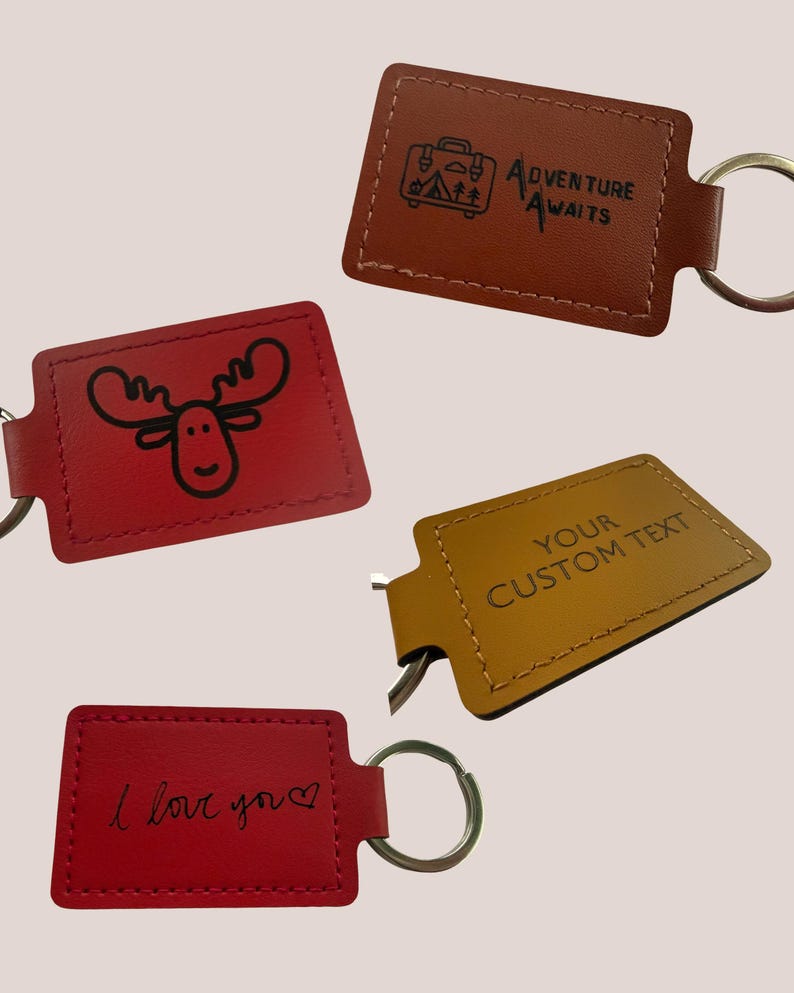 May include: Four leather keyrings in red, brown, and gold. One red keyring has a moose illustration, another says "I love you", and a brown one says "Adventure Awaits". The gold keyring says "Your Custom Text".