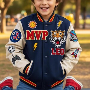 May include: A navy and beige varsity jacket with various patches. The jacket displays the word "MVP", a tiger graphic, and the name "LEO". Patches include a sun, a football, a rocket, and a games controller.