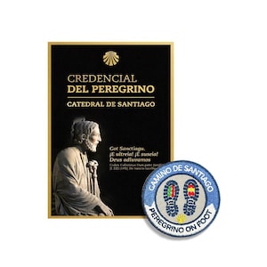 May include: A black rectangular Credencial del Peregrino document from the Catedral de Santiago featuring a statue of Saint James and a circular embroidered patch with blue borders, white center, and two footprints with the text Camino de Santiago.