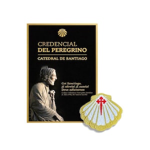 Op de afbeelding: Een zwart rechthoekig Credencial del Peregrino-document van de Catedral de Santiago met een gouden sint-jakobsschelppictogram, tekst en een standbeeld, naast een geborduurde patch in de vorm van een witte en gouden sint-jakobsschelp.