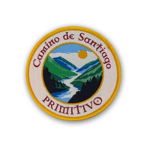 May include: Embroidered patch with a scenic landscape design. The patch features a river winding through green and blue mountains under a yellow sun. Text around the edge reads "Camino de Santiago PRIMITIVO" in red and white.