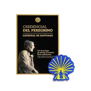 Op de afbeelding: Een zwart rechthoekig Credencial del Peregrino-document van de Catedral de Santiago met een gouden sint-jakobsschelppictogram, tekst en een standbeeld, vergezeld van een blauwe en gele geborduurde sint-jakobsschelppatch met een figuur.