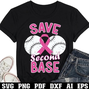 May include: A black short-sleeved t-shirt featuring a graphic with two white baseballs, a pink awareness ribbon, and the text "SAVE Second BASE" in pink lettering. The design is centered on the chest of the shirt, which is displayed flat.