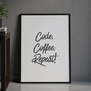 May include: A black-framed print with the text "Code, Coffee, Repeat!" in a cursive font. A laptop, a small potted plant, and books are on a dark brown desk. The print leans against a dark grey wall. A dark grey rug is in the foreground.