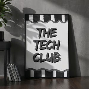 Può includere: Un poster incorniciato con la scritta "THE TECH CLUB" in grassetto, nero, stile pennellata. Il poster ha uno sfondo bianco con strisce ondulate bianche e nere. Sullo sfondo una scrivania nera con un laptop e una pianta in vaso.
