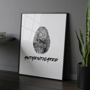May include: Framed black and white art print featuring a detailed fingerprint design. The word "AUTHENTICATED" is written in a stylized font below the fingerprint. The artwork is displayed in a modern setting.