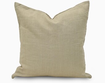 May include: A square, beige linen pillow with a soft, textured appearance. The pillow has a simple design and a neutral color, suitable for various home decor styles. The pillow is a decorative item for a bed or sofa.