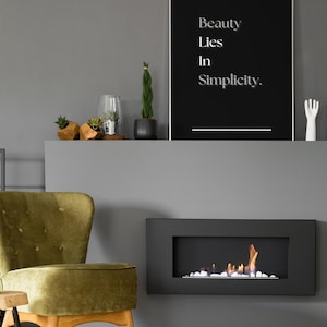 Peut inclure: Intérieur moderne avec un poster noir portant l'inscription "Beauty Lies In Simplicity". On y trouve un fauteuil en velours vert, une cheminée noire avec des flammes et des plantes décoratives.