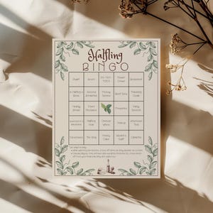 May include: A cream-colored Halfling Bingo game card with green floral border and text. The card features a grid with various themed words like "Dwarf," "Acorn," and "Cheese Wheel." Instructions are at the bottom.