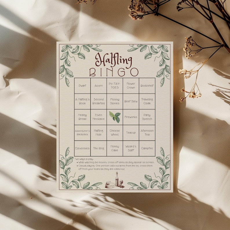 May include: A cream-colored Halfling Bingo game card with green floral border and text. The card features a grid with various themed words like "Dwarf," "Acorn," and "Cheese Wheel." Instructions are at the bottom.