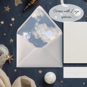 Puede incluir: Un sobre blanco con un interior temático de cielo, con nubes y estrellas. Se muestra el texto "Comes with 7 size options". Artículos de papelería adicionales y estrellas decorativas están dispersos sobre una superficie azul oscuro.
