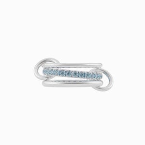 May include: A silver ring featuring three linked bands. The central band is embellished with a row of small, pale blue gemstones. The ring has a contemporary, minimalist design, set against a white backdrop.