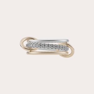 May include: A multi-tone ring featuring a linked design. The ring combines gold and silver tones, with a central band adorned with small, sparkling stones. The design is modern and elegant, suitable for everyday wear or special occasions.