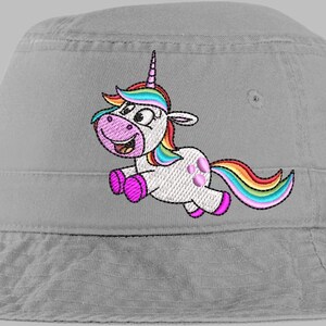 May include: A light gray bucket hat featuring an embroidered cartoon unicorn. The unicorn has a white body, pink hooves, and a rainbow mane and tail. The unicorn is smiling and appears to be jumping.