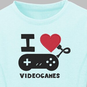 May include: A light blue sweatshirt with the phrase "I ❤️ VIDEOGAMES" embroidered on the front. The design features a black controller, a red heart, and the text in black. The sweatshirt has a crew neck and long sleeves.