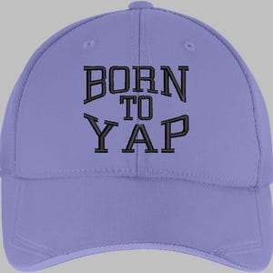 Peut inclure: Casquette de baseball lilas avec l'inscription brodée en noir "BORN TO YAP". La casquette a une visière incurvée et un bouton sur le dessus. Fabriquée dans un tissu résistant.
