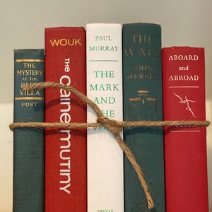 May include: A stack of five hardcover books with red, white, and green covers. The books are tied together with twine. The titles of the books are "The Caine Mutiny", "The Mark", "The Wall", "The Mystery at the Blue Villa", and "Aboard and Abroad".