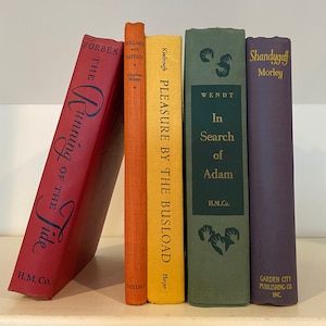 May include: A collection of five hardcover books with different colored spines. The books are arranged vertically on a shelf. The titles of the books are "The Running of the Tide", "Bolland and Britain", "Pleasure by the Busload", "In Search of Adam", and "Shandygaff".