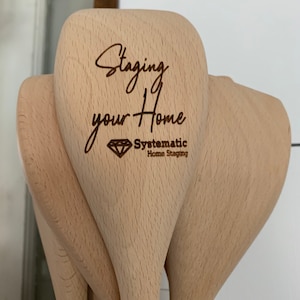 以下が含まれることがあります： 木製のスプーンのセットで、1つのスプーンに「Staging your Home」というテキストと「Systematic Home Staging」のロゴが刻まれています。