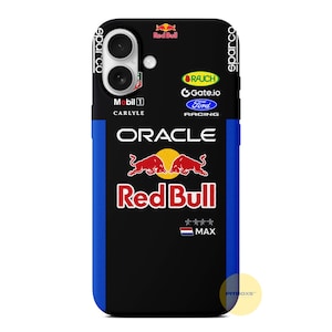 Può includere: Custodia per telefono nera con una striscia blu e il logo Red Bull Racing. La custodia presenta il logo Oracle, i loghi degli sponsor e la parola "MAX". La custodia ha un ritaglio per doppia fotocamera.