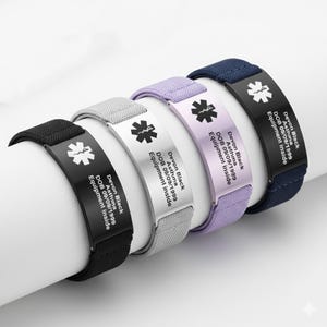 Peut inclure: Quatre bracelets d'alerte médicale noirs, gris, blancs et lavande. Chaque bracelet comporte une plaque métallique avec un symbole médical et le texte "Devon Black, Asthma, DOB 09/09/1999, Equipment Inside."