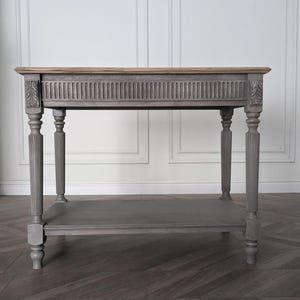 Könnte beinhalten: Eine graue Konsolentisch mit einer Tischplatte aus Naturholz. Der Tisch hat geschnitzte Details an den Beinen und der Zarge sowie ein unteres Regal. Der Tisch ist ca. 91 cm lang, 41 cm breit und 76 cm hoch.